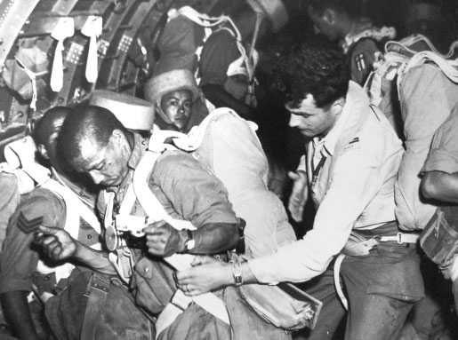 Nepalese soldiers, called Gurkhas after the district of Gorkha in Nepal, prepare for a parachute jump with help from RCAF aircrew in a DC-3 Dakota transport aircraft. [DND/LAC/PL-60632]