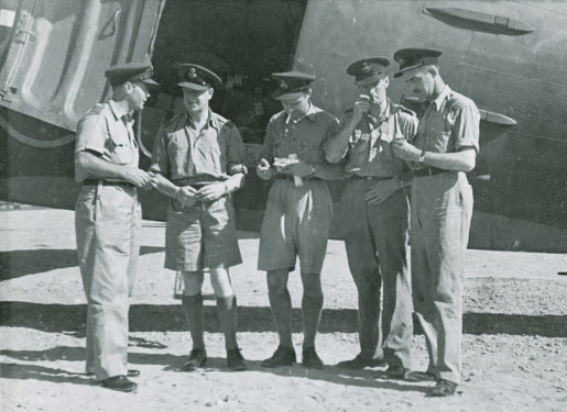 RCAF officers assemble at an airfield in Cairo, Egypt, while en route to Asia in 1944. From left are Wing Commander Paul Mathews, Wing Cmdr. H.B. Norris, Squadron Leader W.B. Woods, Wing Cmdr. Lionel Kent, and Sqdn. Ldr. W.W. McKay. [Canadian War Museum/19650071-019_14975]