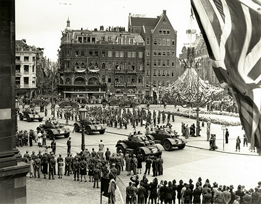 Celebrating the return of Queen Wilhelmina, Canadian troops and Dutch groups parade past the Royal Palace and Dam Square in Amsterdam on  June 28, 1945. [B.J. Gloster/DND/LAC/PA-166390]