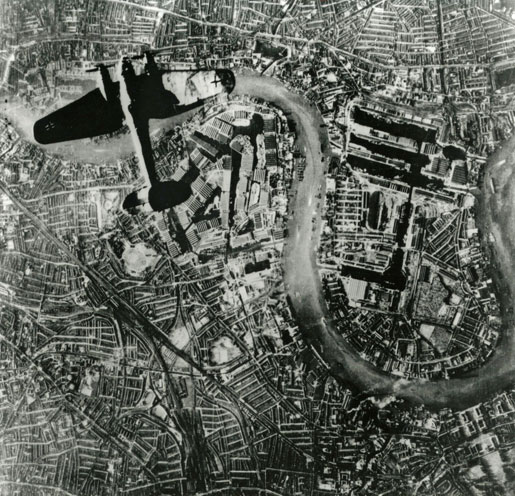 Photographed by a German Luftwaffe photographer, a German Heinkel HE-111 aircraft flies over Wapping in London’s East End on Sept. 7, 1940. [DND/LAC/PA-037470]