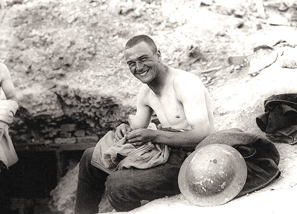 A soldier picks lice from the seams of his shirt in 1918.