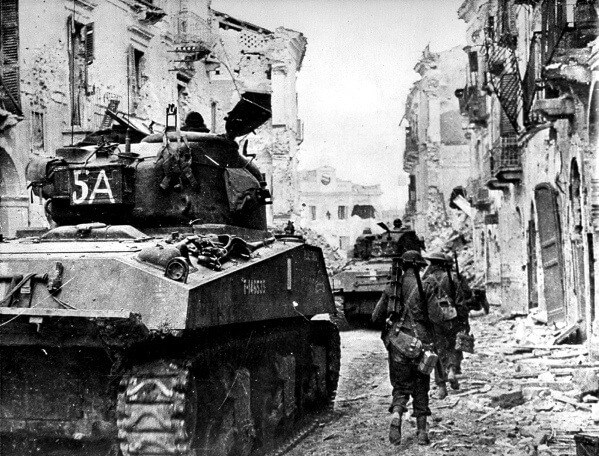 Tanks and infantry advance through the ruins of Ortona. [LAC]